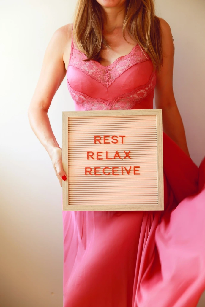 Woman holds a sign: "rest, relax, receive."